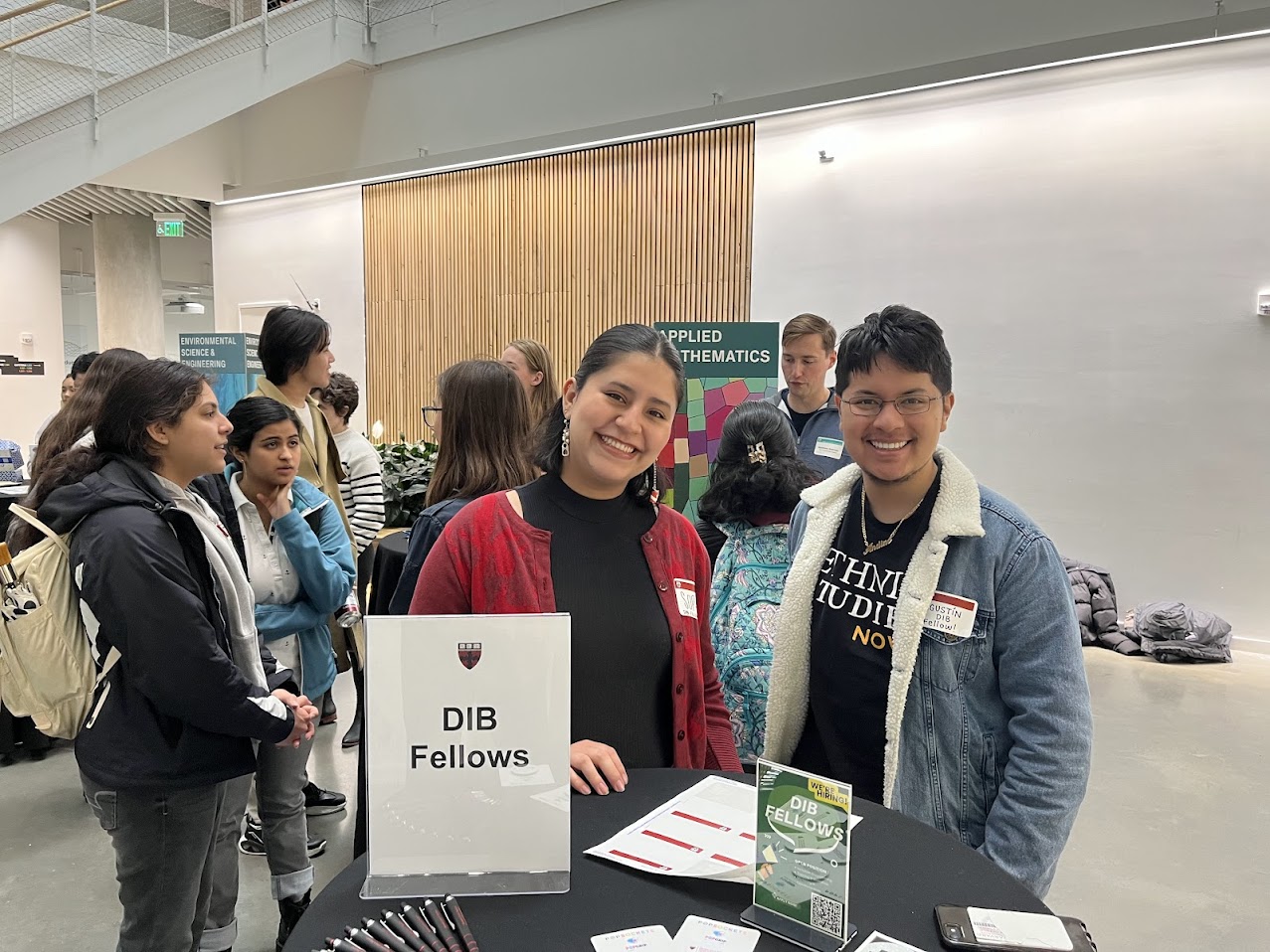 Two students smiling behind a table with a tent that reads "DIB Fellows"