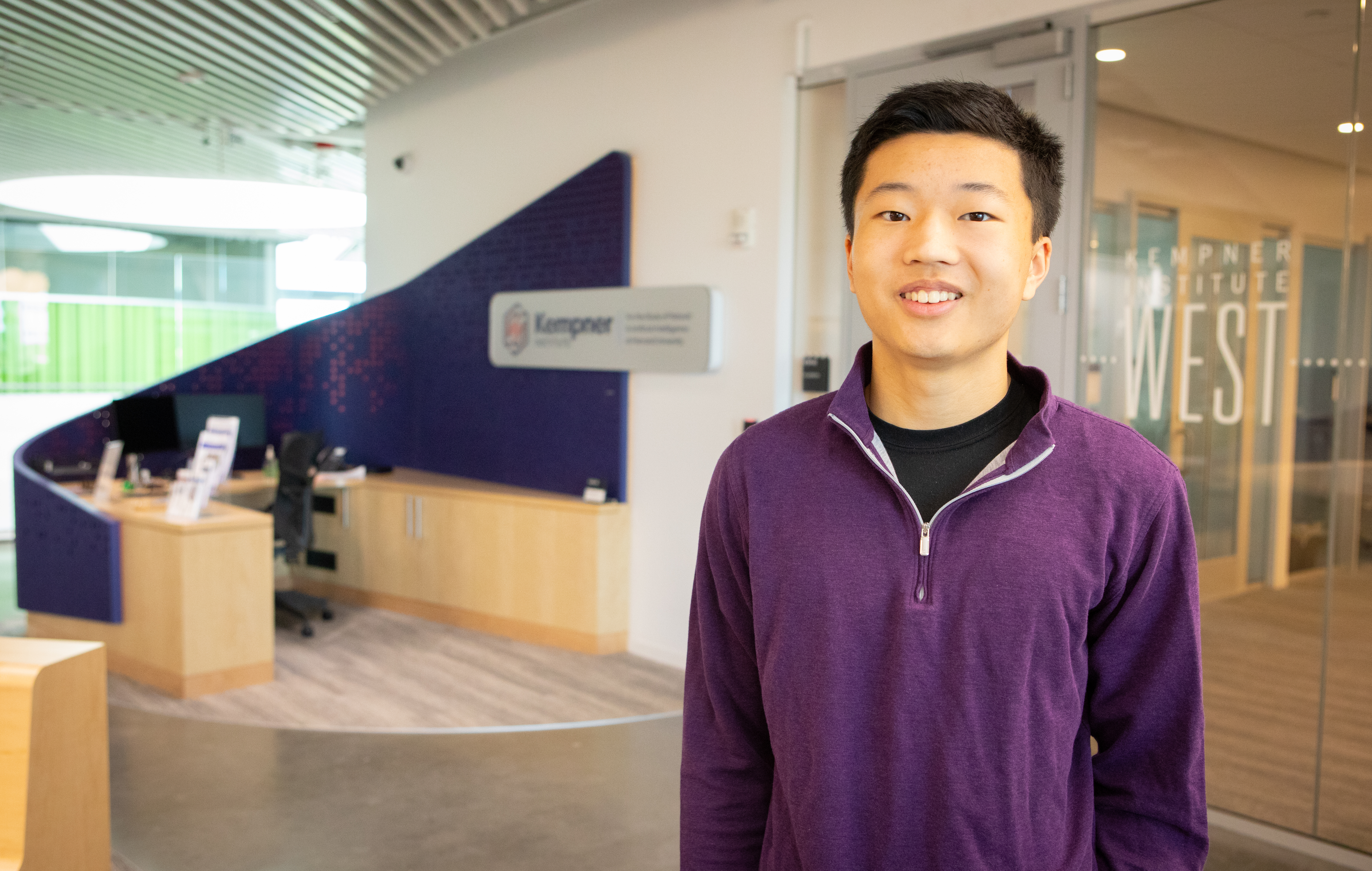 Harvard SEAS student Benjamin Choi in front of a sign for the Kempner Institute for the Study of Natural and Artificial Intelligence