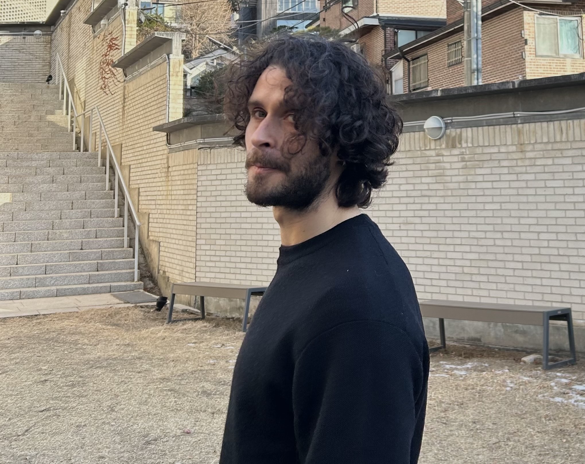 Harvard SEAS alum Theo Guenais by a brick wall and stairs