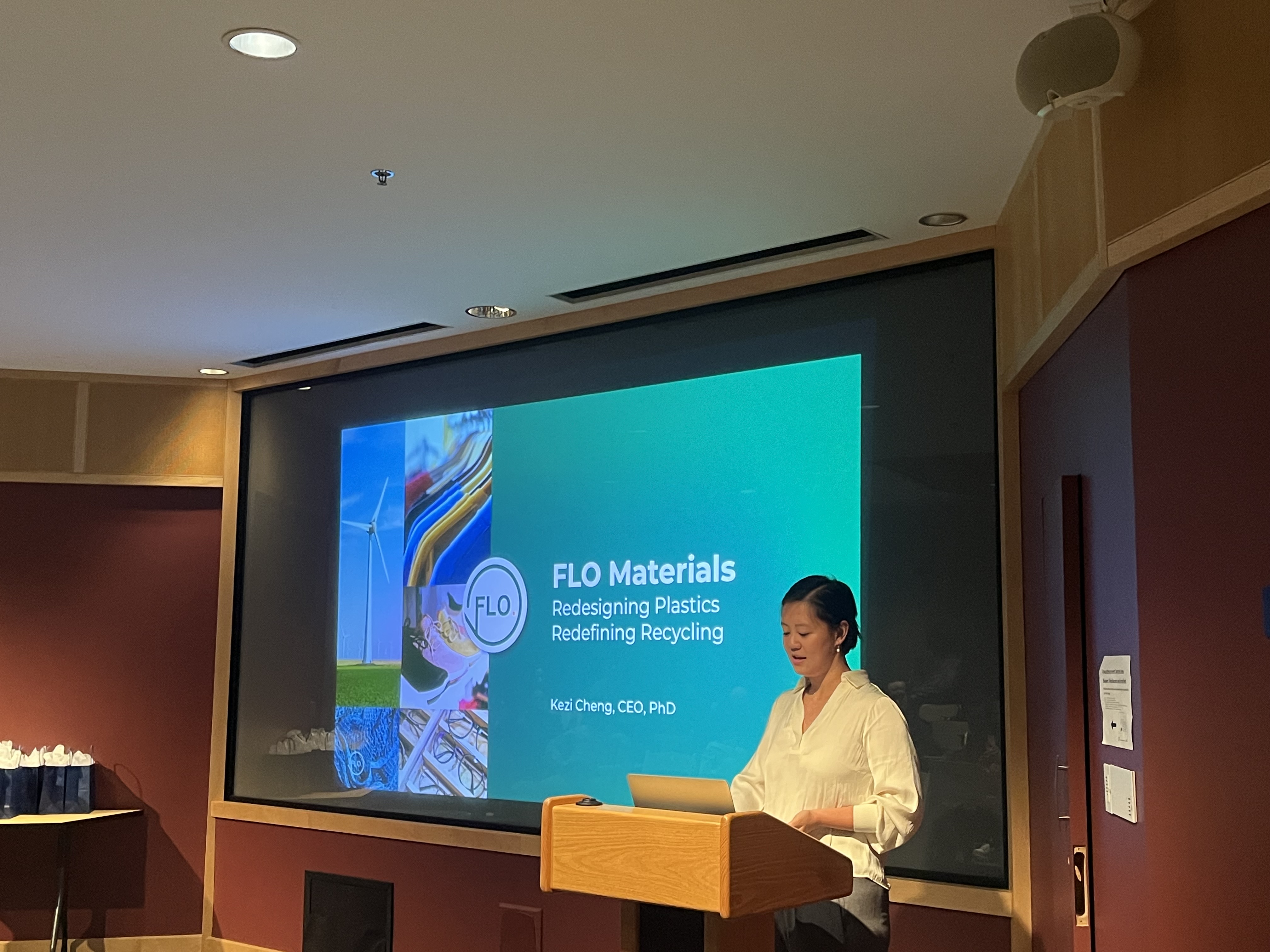 Harvard SEAS student Kezi Cheng, Ph.D. '21, behind a lectern with a digital projection for her company FLO Materials