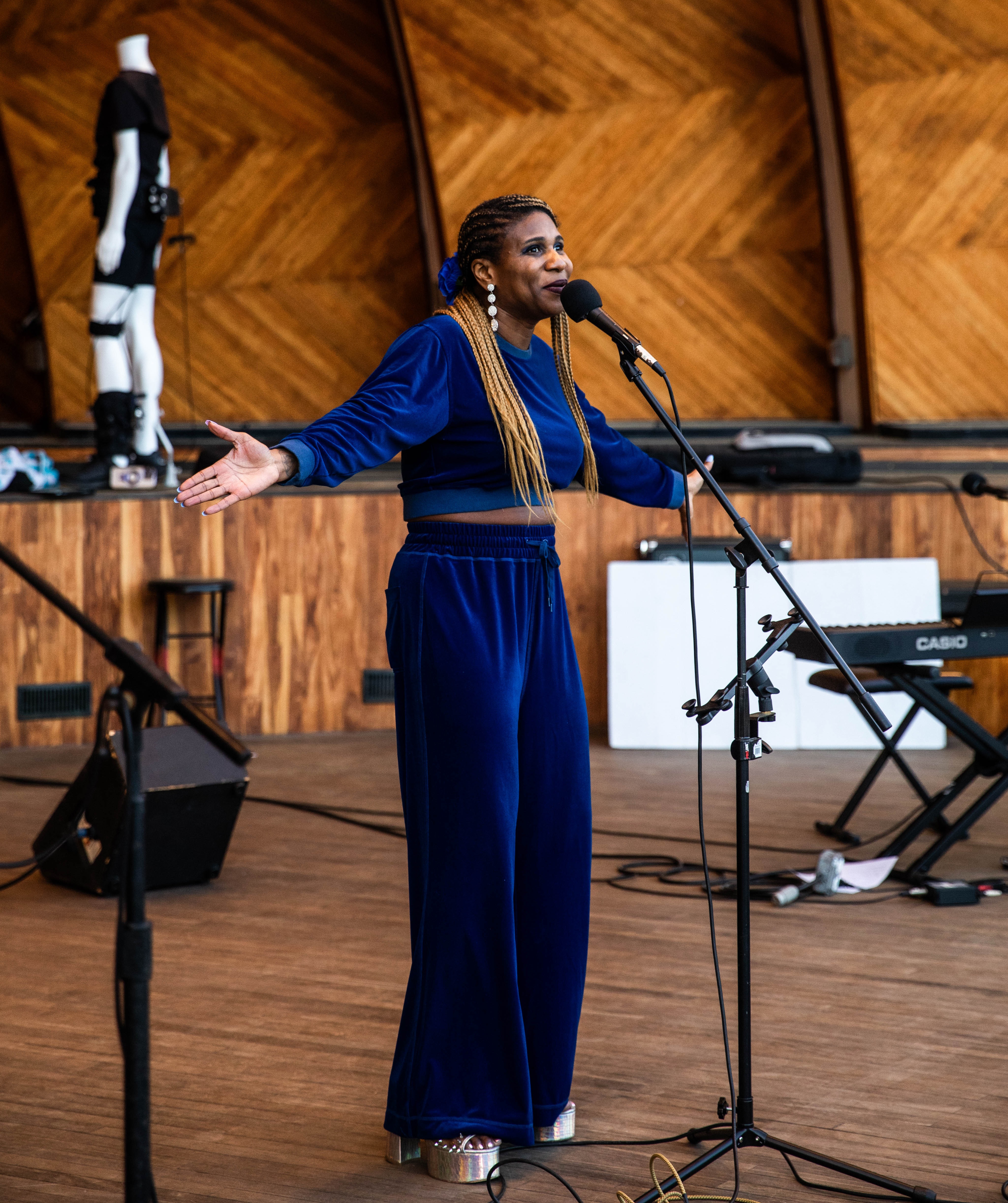Performing artist Lachi sings into a microphone at the Hatch Memorial Shell in Boston