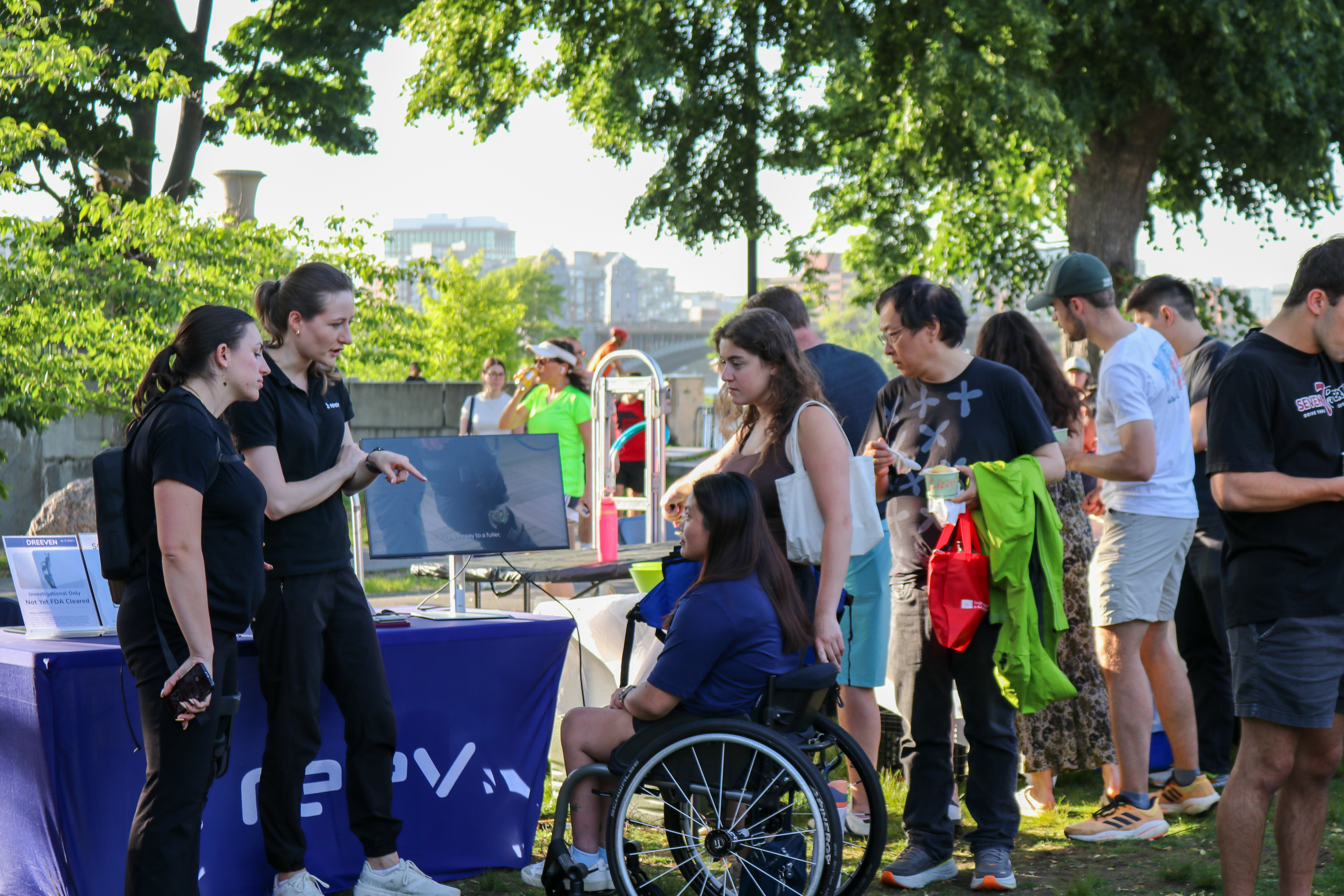 A group of people, one in a wheelchair, chat at a table for technology start-up REEV