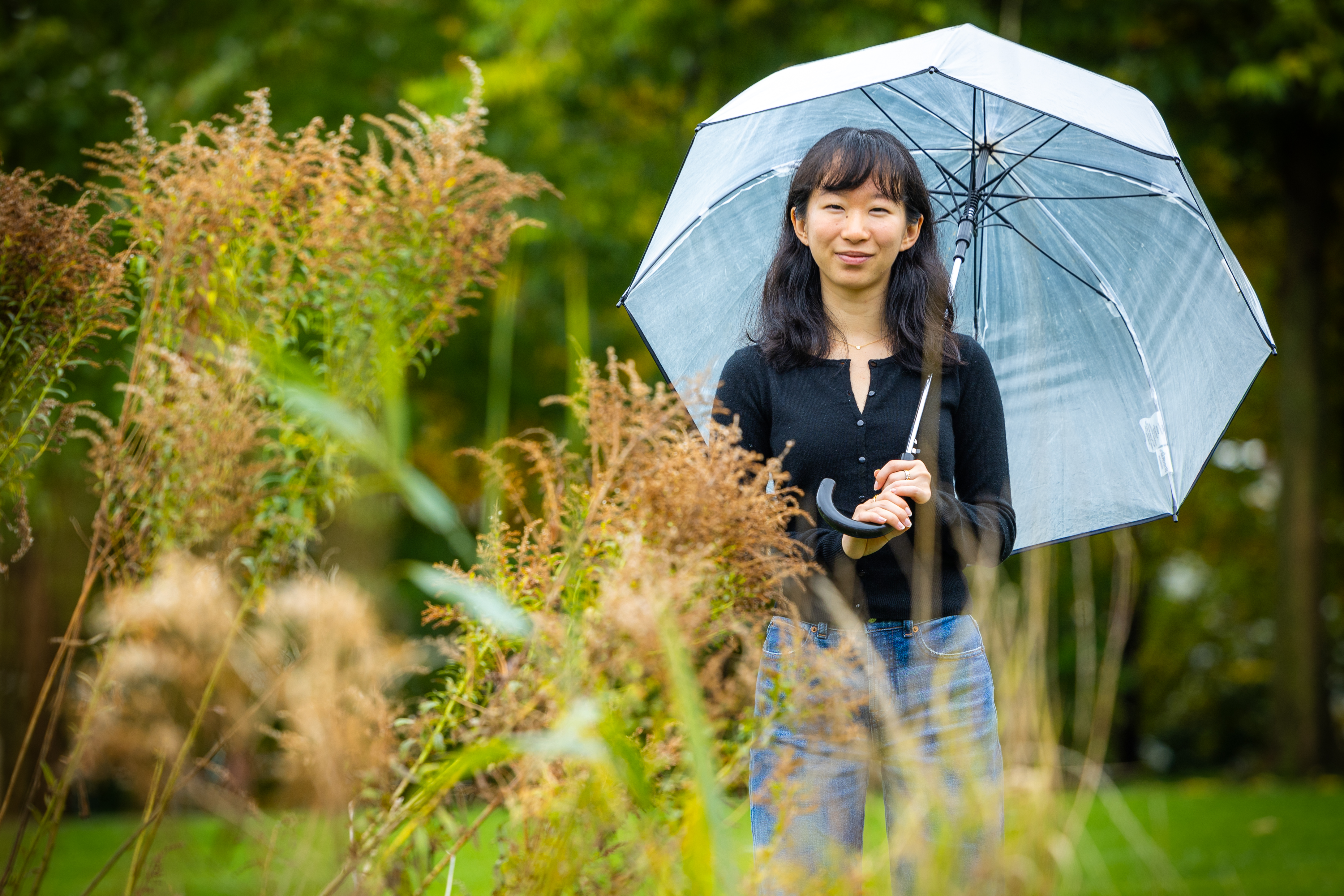 Harvard SEAS student Hannah Guan holding an umbrella next to plants