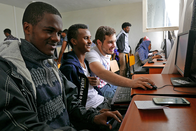 Dimitri Karev, A.B. ’21 (right) reviews coursework with Ethiopian high schoolers in the AddisCoder program. (Photo courtesy of AddisCoder)