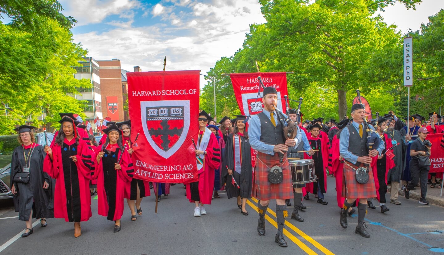 Harvard SEAS and GSAS banners, bagpipers, students in Crimson regalia