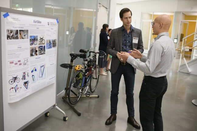 A Nexus attendee learns about Sebastian Lindner-Liaw's senior capstone project, a compressed-air assistive bicycle