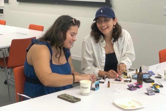 Harvard members Daria Paulis and Monica Figueroa surrounded by perfume ingredients and samples on a white table