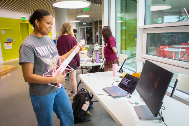 Harvard SEAS student Madison Hussey playing a pink guitar-shaped game controller