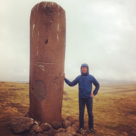Winston Yu stands next to a Vishap stone in Armenia