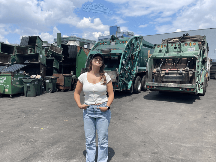 SEAS junior Sofia Giannuzzi standing in a parking lot front of a fleet of garbage trucks