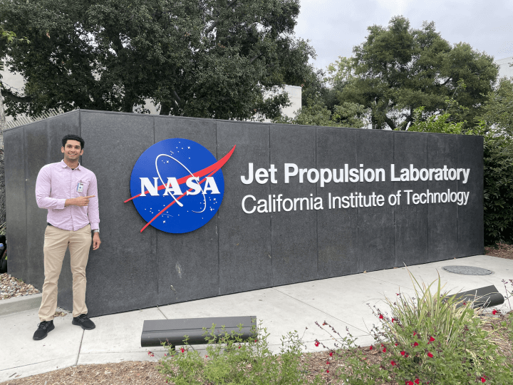 Rohil Dhaliwal, A.B. '25, pointing at a sign for NASA’s Jet Propulsion Laboratory in Pasadena