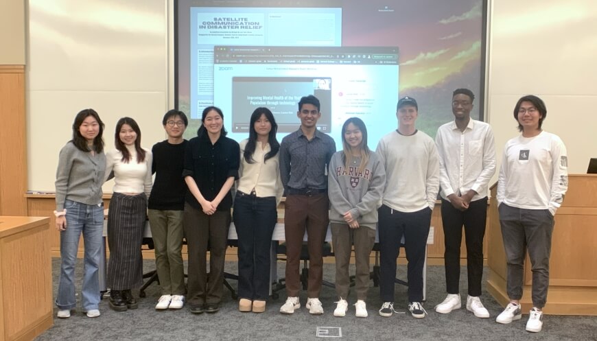 Ten Harvard students standing in front of a projected image