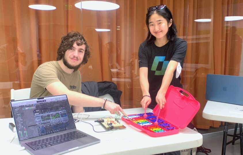Two Harvard students playing a glockenspiel connected to an electronic synthesizer