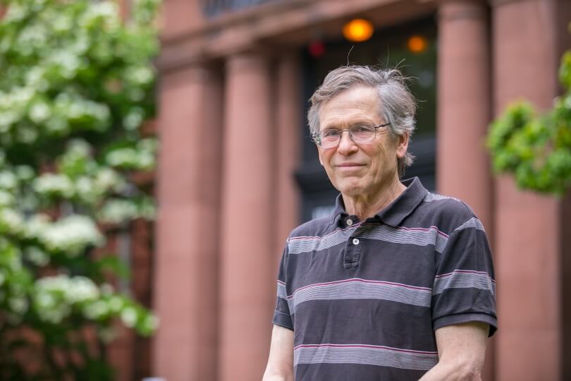 Harvard professor Steven Wofsy in front of a building with red columns and trees