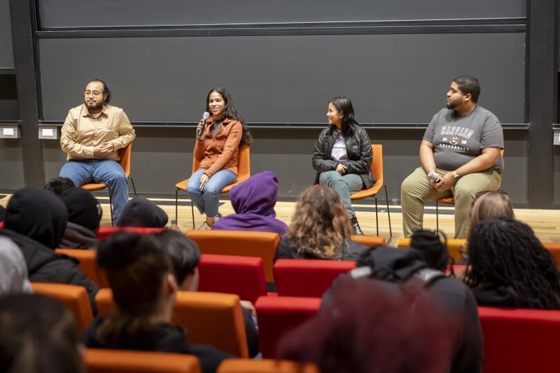 Four students sitting on chairs in an event panel
