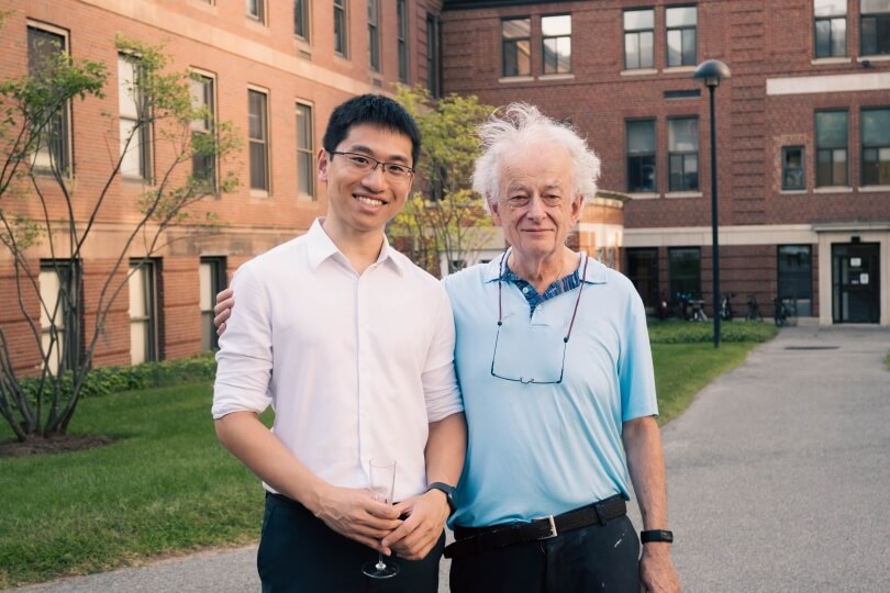 Former SEAS graduate student Soon Wei Daniel Lim and professor Federico Capasso standing in front of red brick buildings in Harvard Yard
