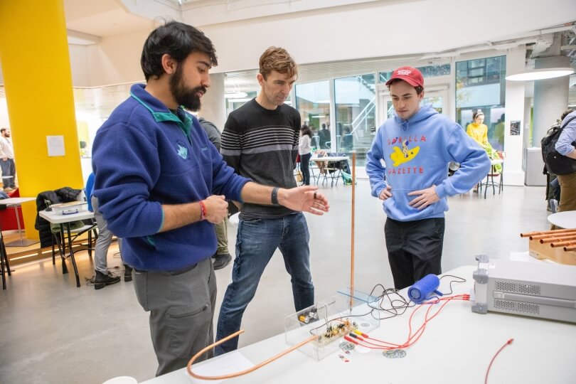 two Harvard students and SEAS professor Robert Wood standing around a theremin