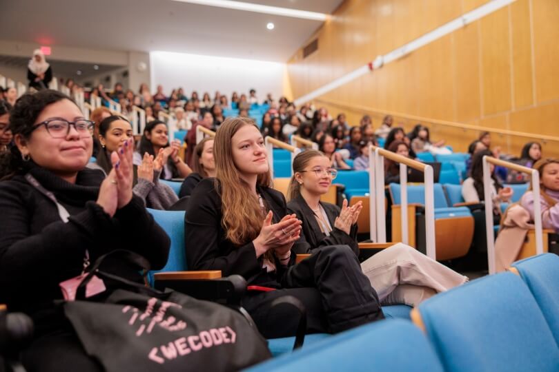 A group of students applauding in a lecture hall