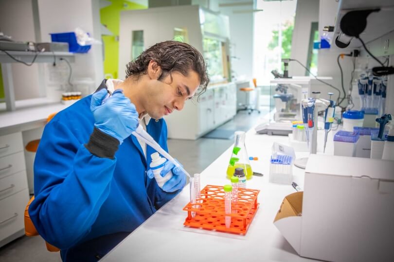 Harvard SEAS student Manav Bansal using a micropipette at a lab station