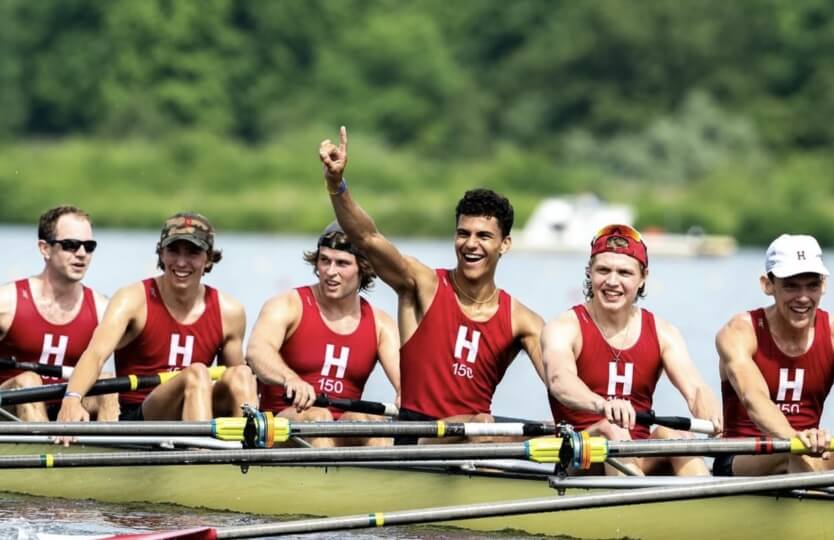 A group of male Harvard students wearing red jerseys on a racing shell