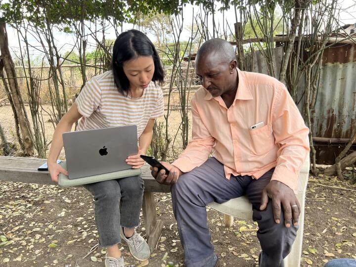 Harvard SEAS GSD alum Caroline Fong holding a laptop with a farmer holding a smartphone