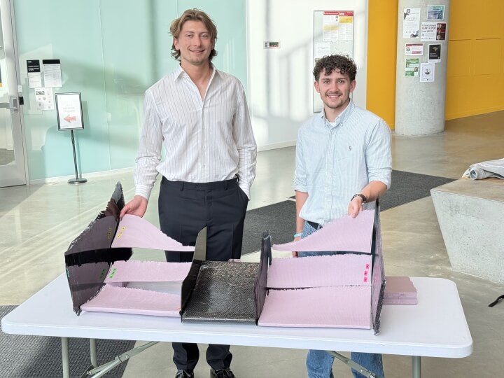Harvard SEAS students Oliver Murcko and Steffan Jones holding pink aerodynamic components for an FSAE racecar