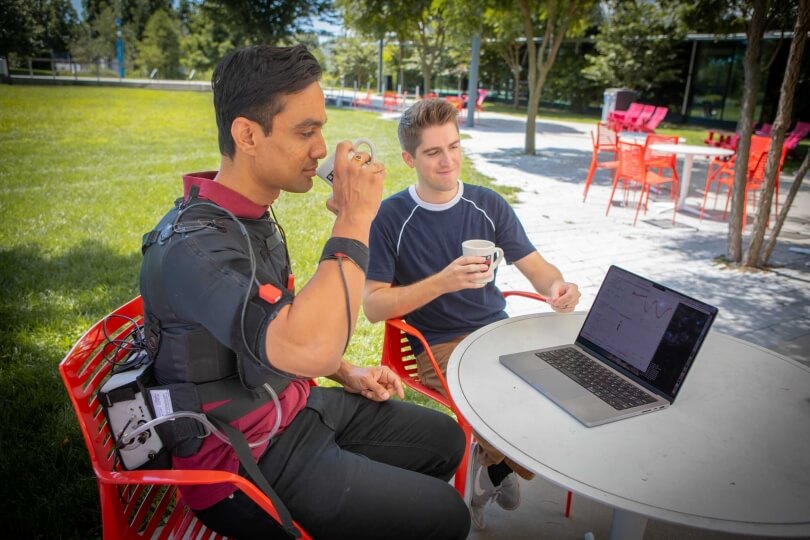 researchers demo wearable robot at a table with laptop and coffee mugs