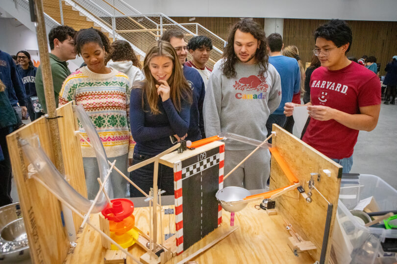 A group of Harvard undergraduate students watching a Rube Goldberg Machine