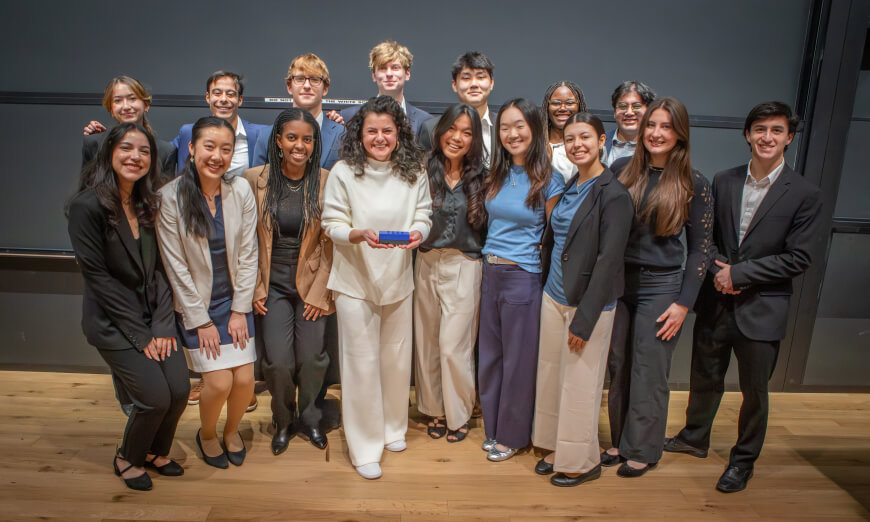 15 Harvard SEAS juniors with Harvard Humanitarian Initiative Executive Director Irini Albanti holding a blue counting tool