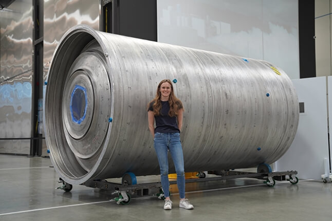 Annie Doris stands in front of a rocket component