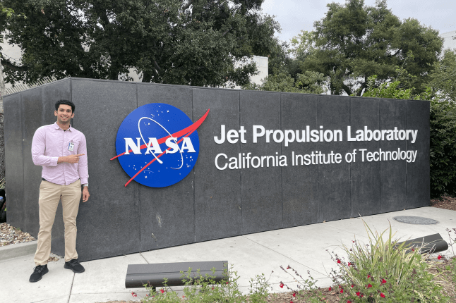 Rohil Dhaliwal, A.B. '25, pointing at a sign for NASA’s Jet Propulsion Laboratory in Pasadena