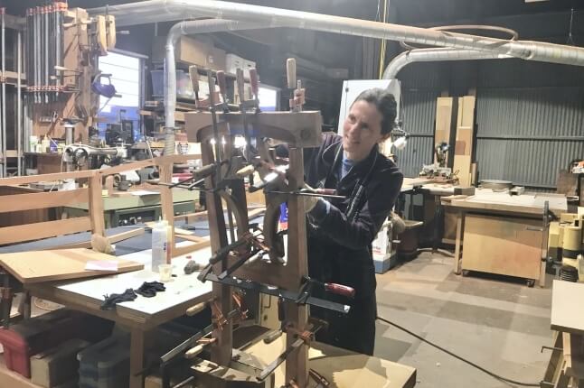 Taimi Barty, A.B. '94, working on a piece of wooden furniture in her studio