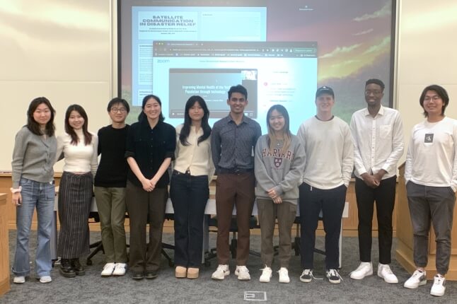 Ten Harvard students standing in front of a projected image