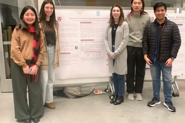 Five SEAS graduate students in front of a poster of their Capstone research project