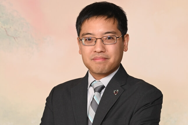Photo of SEAS alum Eugene Beh, A.B./A.M. ‘09, wearing a grey suit and striped tie
