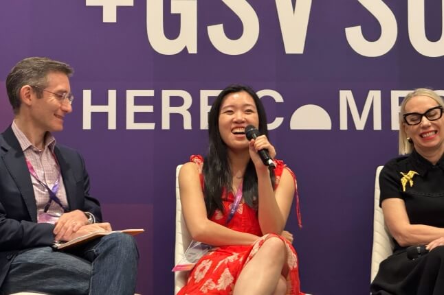 Harvard SEAS Athena Kan, A.B. '19, sitting in a chair and holding a microphone