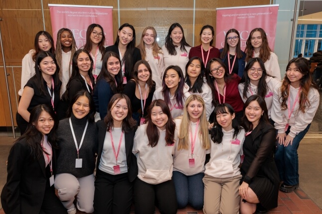 A group of Harvard students standing in front of banners for the 2025 WECode Conference