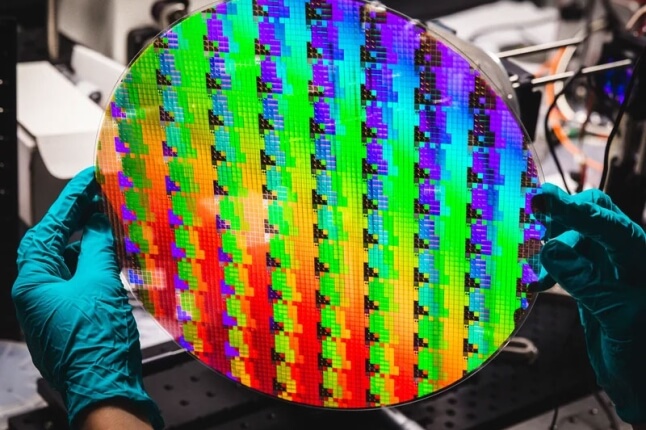 gloved hands holding a metalens
