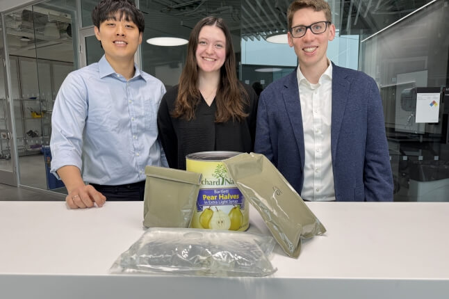 Harvard SEAS students Ray Noh, Faith Schmidt and Josh Halberstadt behind a set of rations pouches and a can of pears