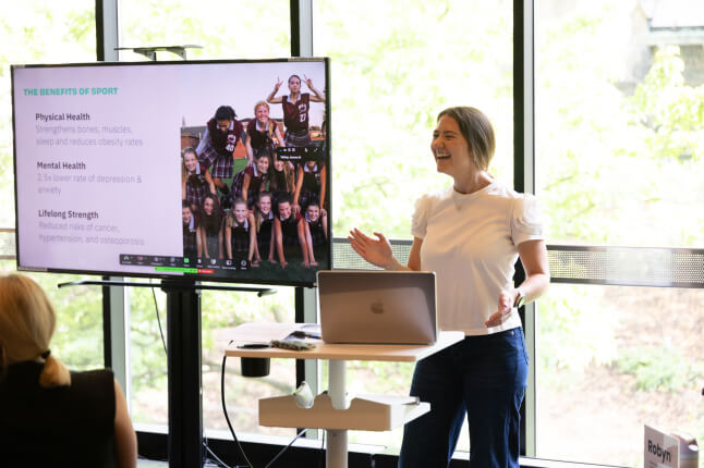 Harvard SEAS GSD adlum Sara Falkson next to a screen depicting the benefits of sports