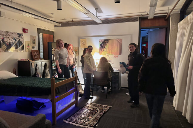 A group of Harvard students in an art installation designed like a bedroom