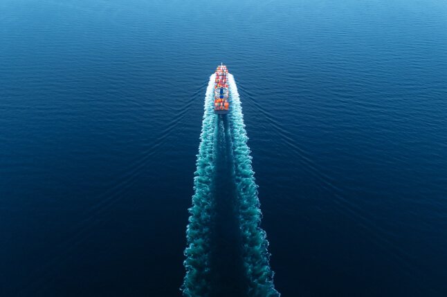 cargo ship with a triangular wake behind it