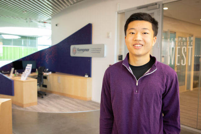 Harvard SEAS student Benjamin Choi in front of a sign for the Kempner Institute for the Study of Natural and Artificial Intelligence