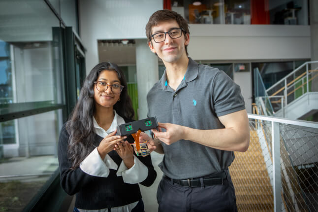 Harvard SEAS students Elsa Oreen and Daniel Kocot holding a pair of smart glasses