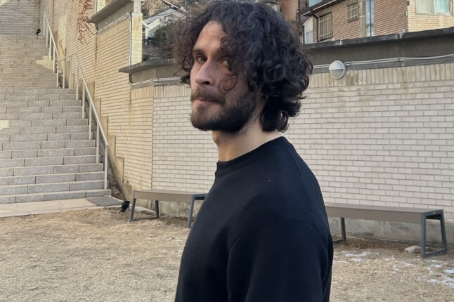 Harvard SEAS alum Theo Guenais by a brick wall and stairs