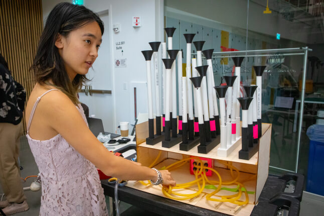 Harvard SEAS student Ellen Pan squeezing pneumatic tubes connected to PVC pipes