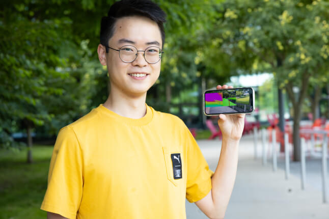 Harvard SEAS student Raymond Liu holding a cell phone displaying an app for the visually impaired