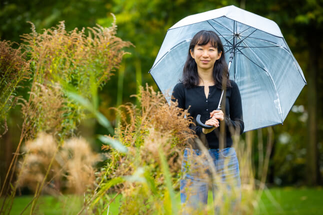 Harvard SEAS student Hannah Guan holding an umbrella next to plants