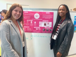 Margaret Cote and Kira Traylor with a poster for the start-up &quot;Lotus&quot;