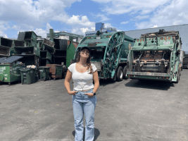 SEAS junior Sofia Giannuzzi standing in a parking lot front of a fleet of garbage trucks